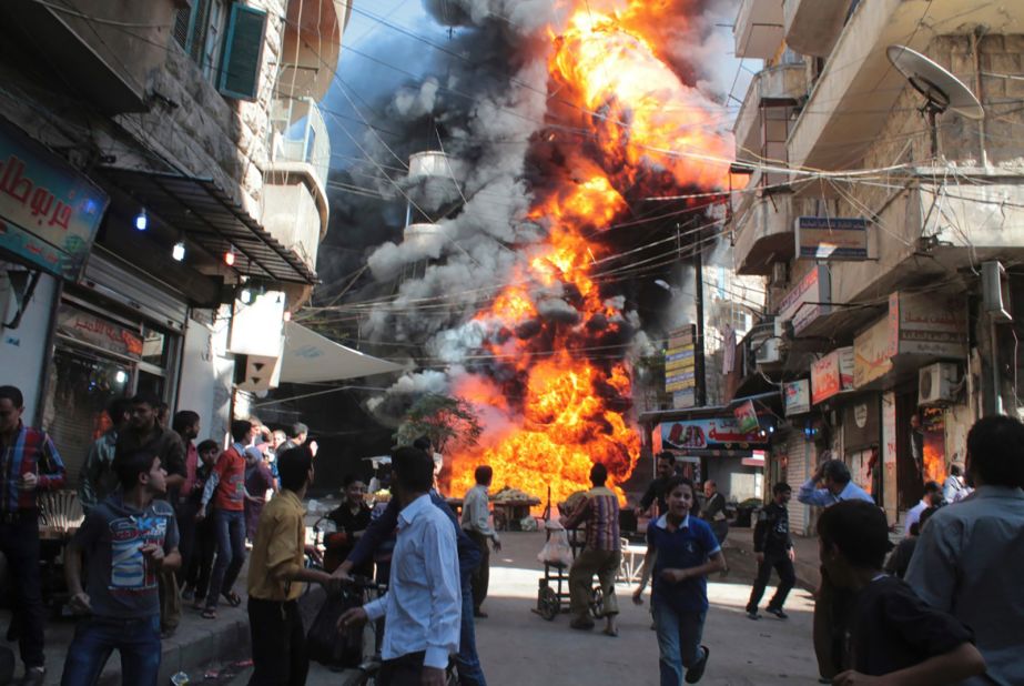 Residents run from a fire at a gasoline and oil shop in Aleppo's Bustan Al-Qasr neighborhood on October 20, 2013. Witnesses said the fire was caused by a bullet from a pro-government sniper.