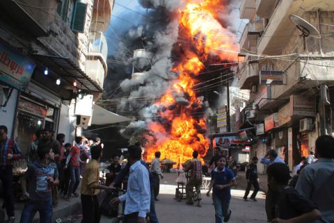 Residents run from a fire at a gasoline and oil shop in Aleppo's Bustan Al-Qasr neighborhood on October 20, 2013. Witnesses said the fire was caused by a bullet from a pro-government sniper.