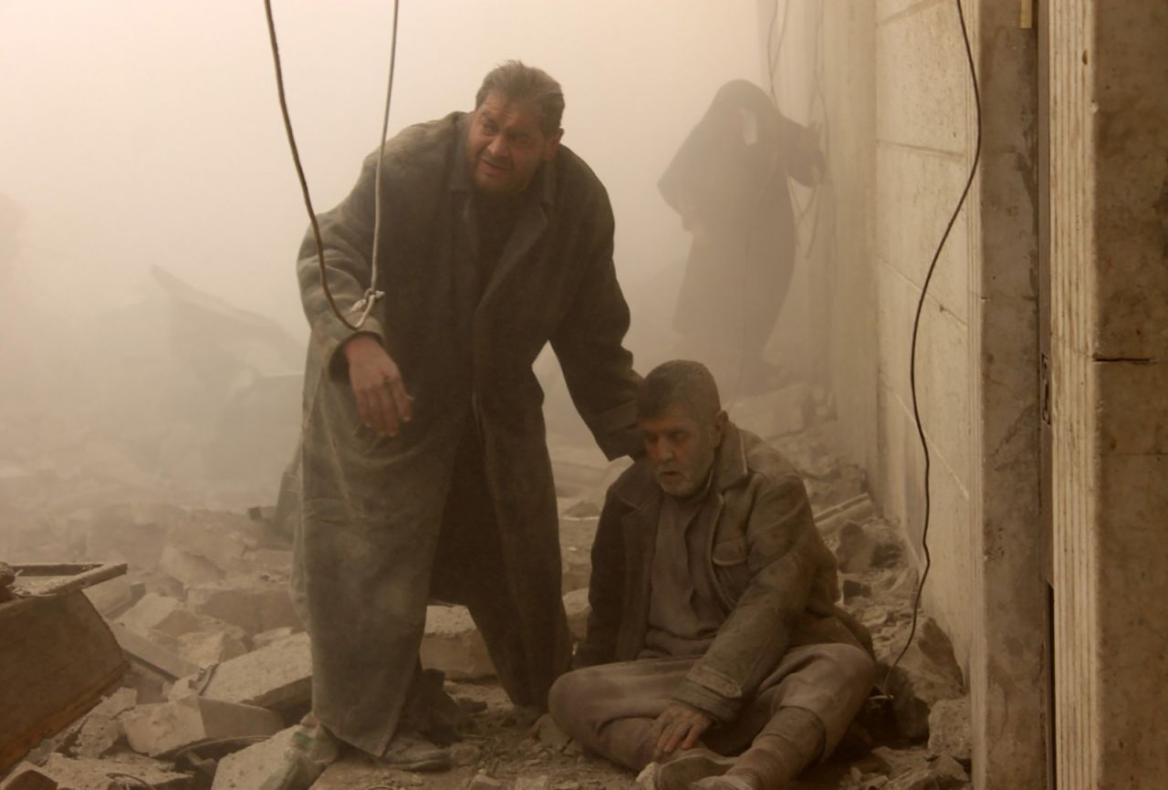 An injured man is helped following an airstrike in Aleppo's Maadi neighborhood on December 17, 2013.