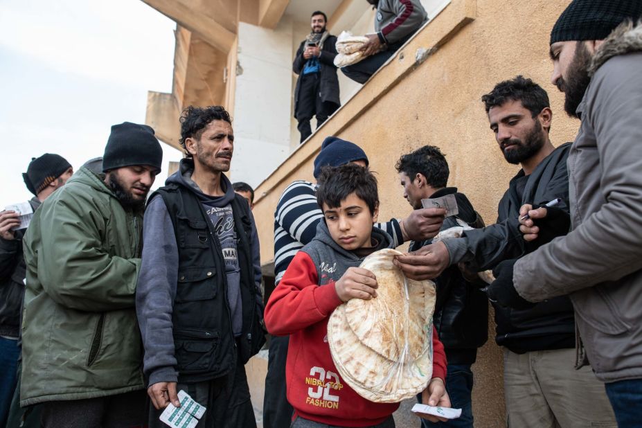 A displaced boy carries a bag of bread as people queue for food distributed by a nonprofit in Idlib on February 19, 2020.