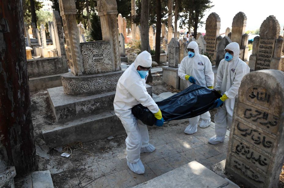 Health workers carry the body of a 62-year-old displaced Syrian man who died of Covid-19, to be buried in the town of Salqin, in Idlib province, on September 17, 2020.