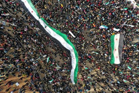 An aerial picture shows Syrians waving the national flag during a gathering in the rebel-held city of Idlib on March 15, 2021, as they mark <a href=