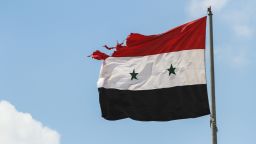 Homs, Syria, September 2013. Syria, September 2013. The flag of Syrian Arab Republic damaged by gunfire evolves in the sky.