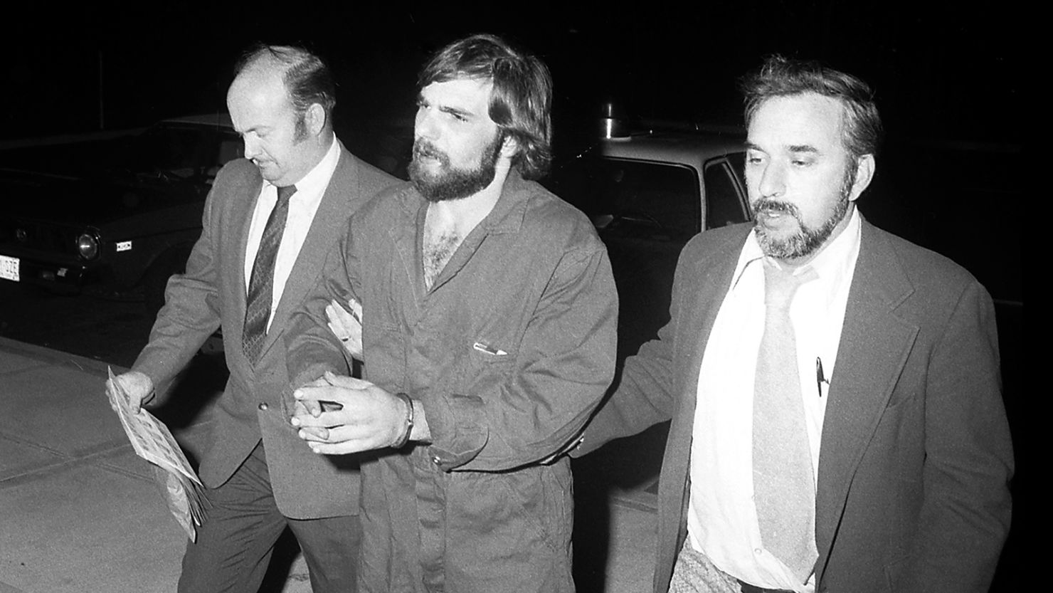 Ronald DeFeo, Jr., pictured here being escorted by detectives in Suffolk County. The killer died at age 69, according to a spokesperson for the New York State Department of Corrections and Community Services.