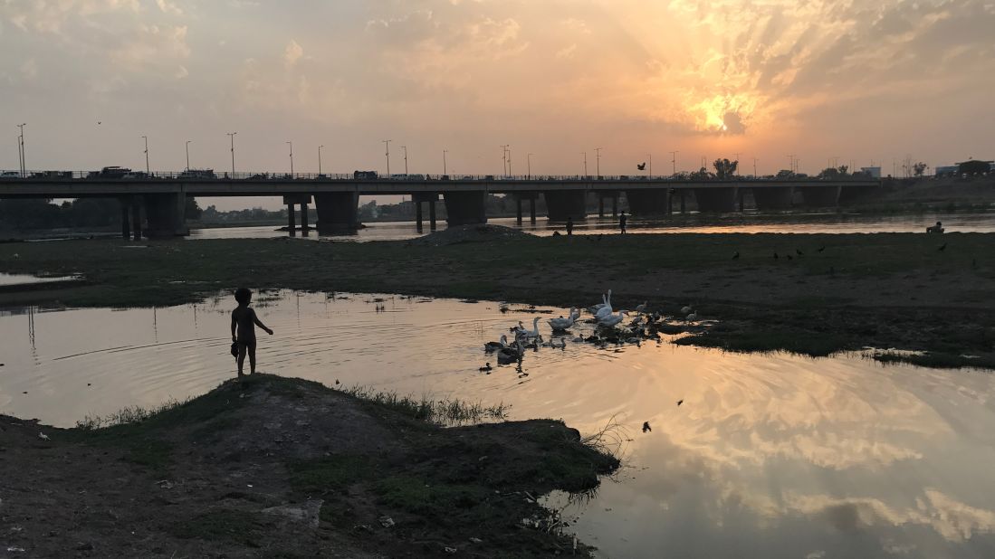 <strong>Peaceful moment:</strong> A boy watches the ducks in the water along with the metro line at Lahore's Ravi Bridge.