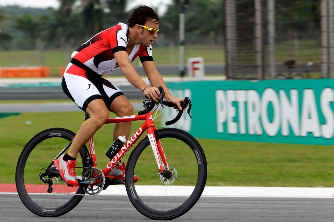 Alonso rides his bicycle around the Malaysia Grand Prix circuit while racing for Ferrari in 2013.  