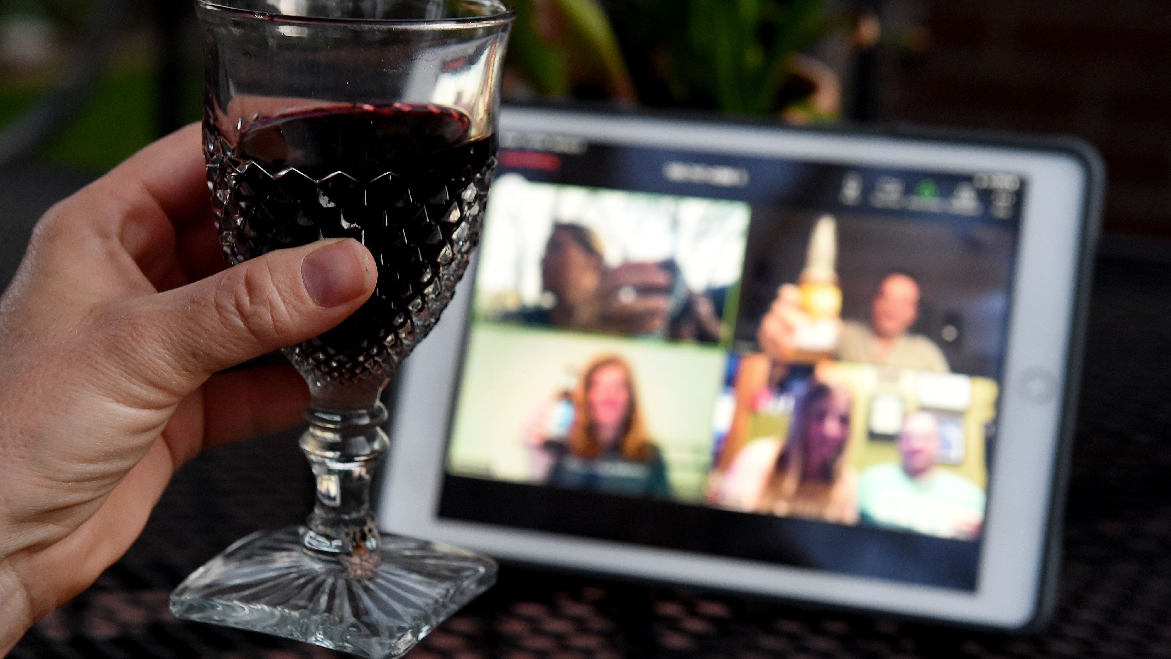 A woman lifts her glass and cheers with friends during a virtual happy hour amid the coronavirus crisis.