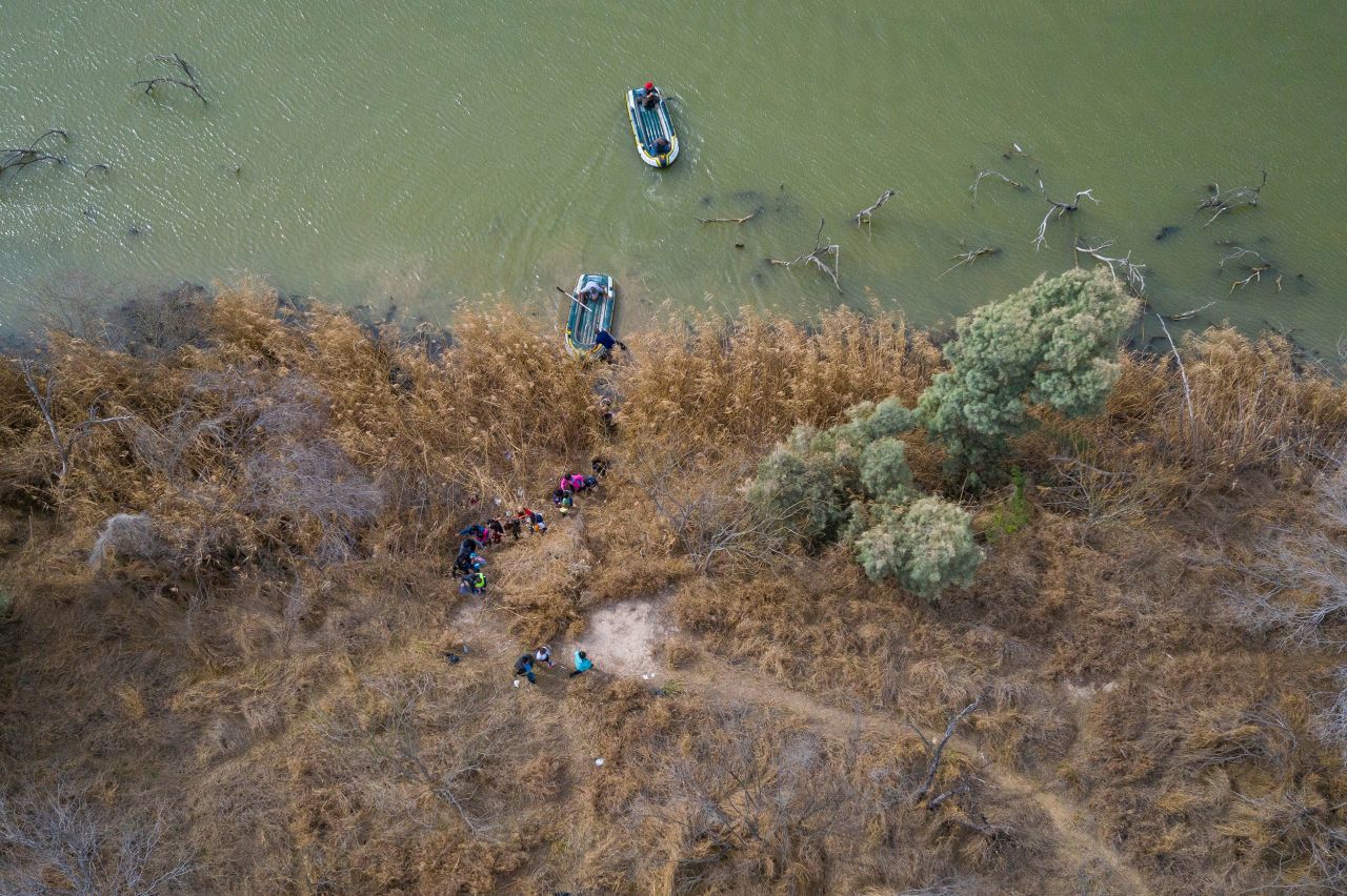 Migrants climb the banks of the Rio Grande into the United States as smugglers on rafts prepare to return to Mexico on March 5.