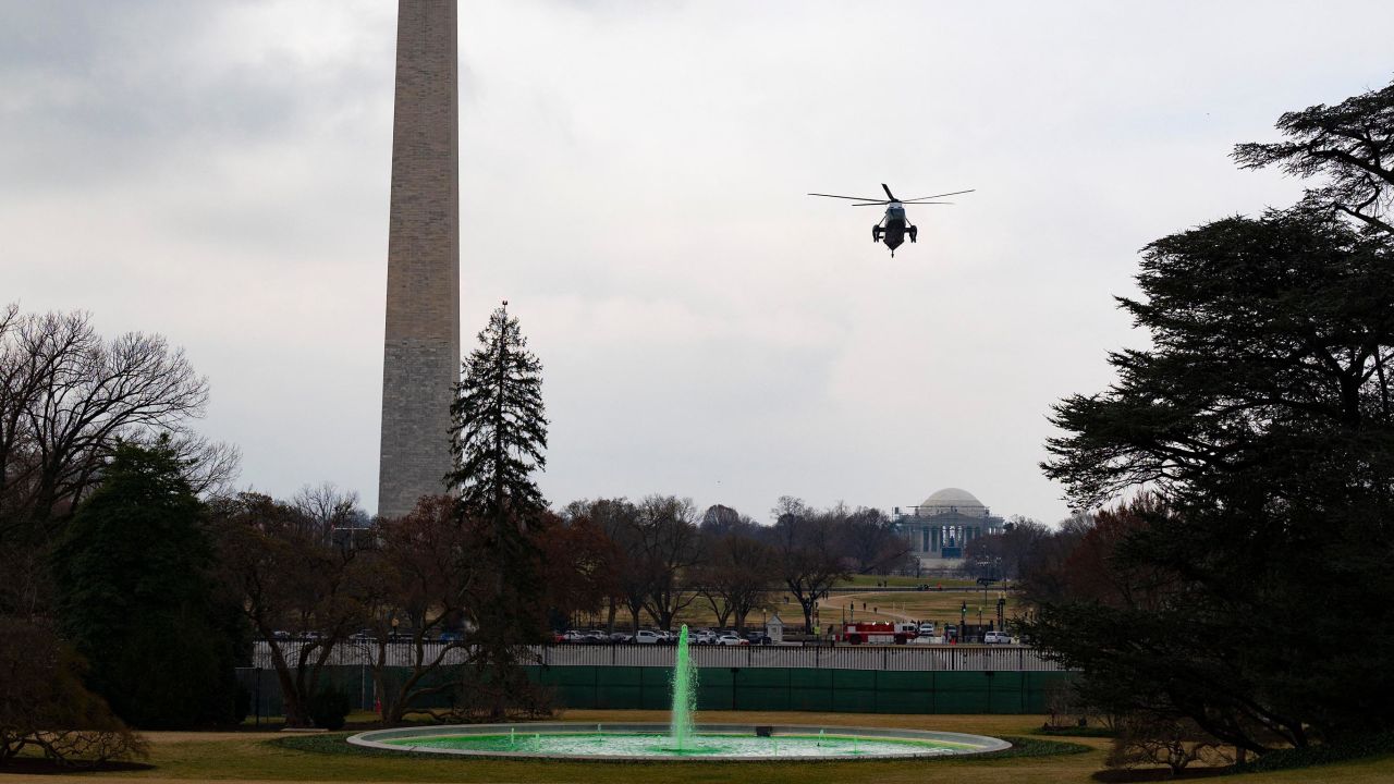 Marine One, carrying US President Joe Biden, flies over the fountain,dyed green for St. Patrick's Day on the South Lawn of the White House, as he arrives on March 17, 2021. 