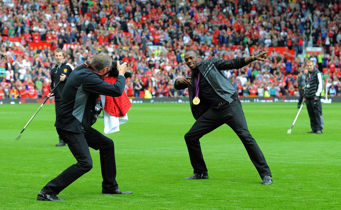 Usain Bolt recreates his famous celebration on the pitch at Old Trafford.