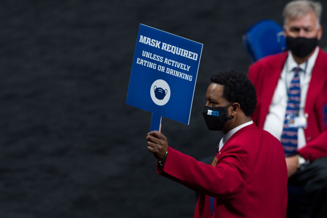 An usher holds up a mask-required sign during the men's Big Ten college basketball tournament on March 11 in Indianapolis.