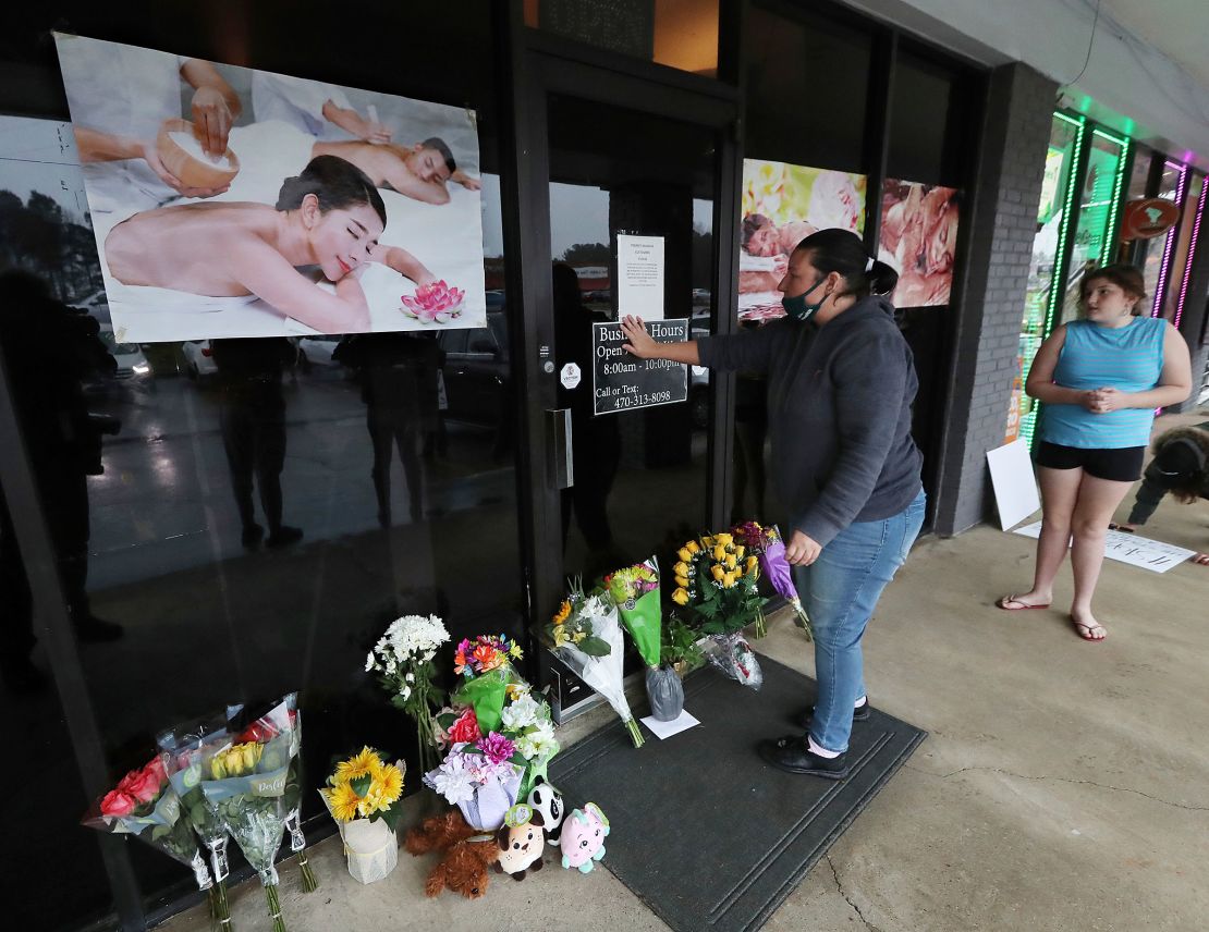 Jessica Lang pauses and places her hand on the door in a moment of grief after dropping off flowers with her daughter Summer at Youngs Asian Massage parlor where four people were killed.