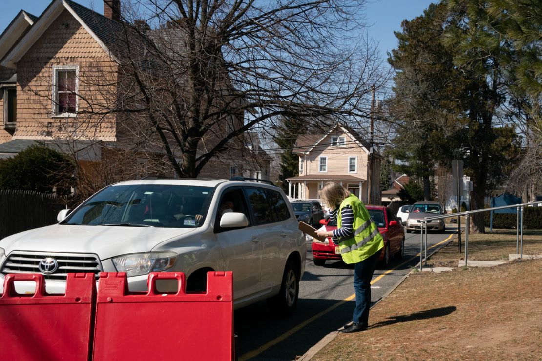 A volunteer collects information from drivers lined up to receive food boxes at the Center for Food Action in Englewood, New Jersey, on March 9, 2021.