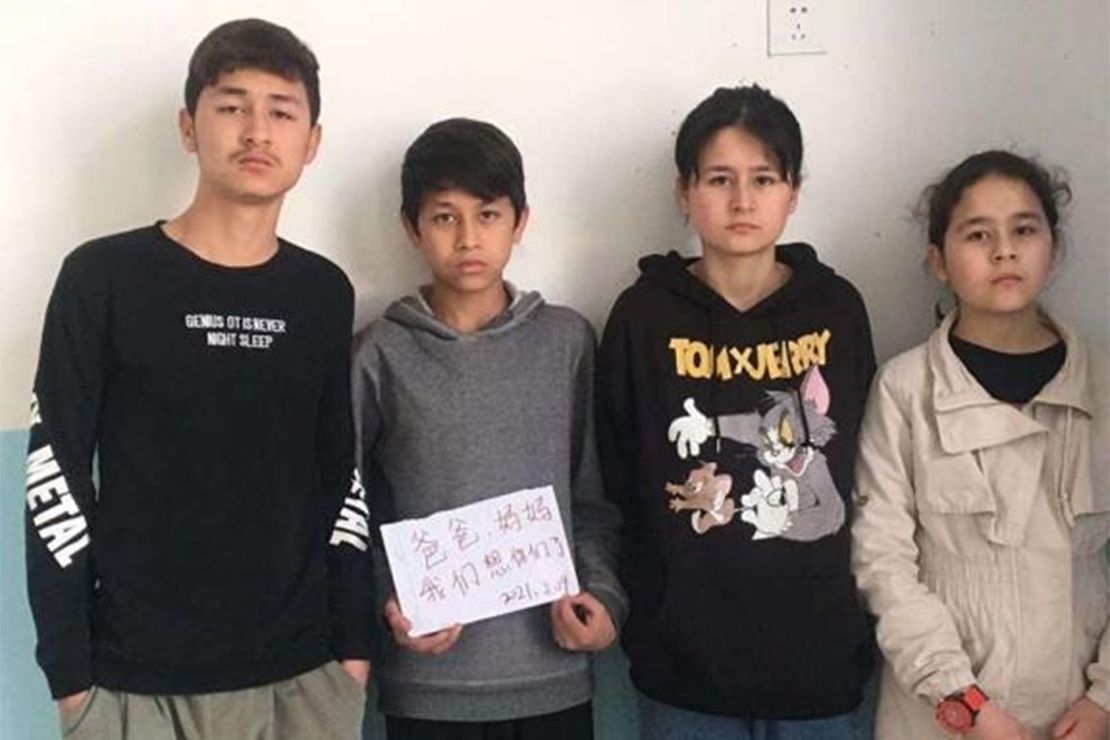 The four siblings -- Zumeryem, Yehya, Muhammad and Shehide -- hold up a sign saying, "Mom, Dad, we miss you," from their state-run orphanage in Xinjiang in 2021.