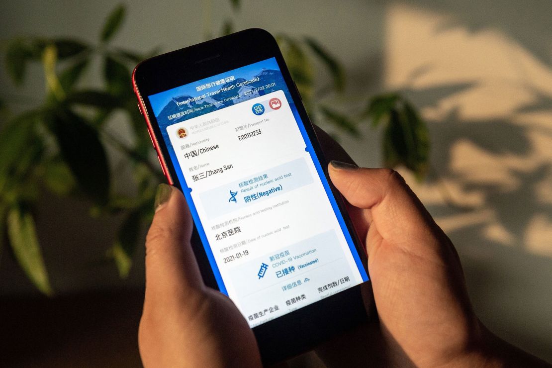 A woman holds a phone displaying a mock-up of Chinas new digital health certificate, the first known implementation of a "virus passport" concept, on March 9, 2021.