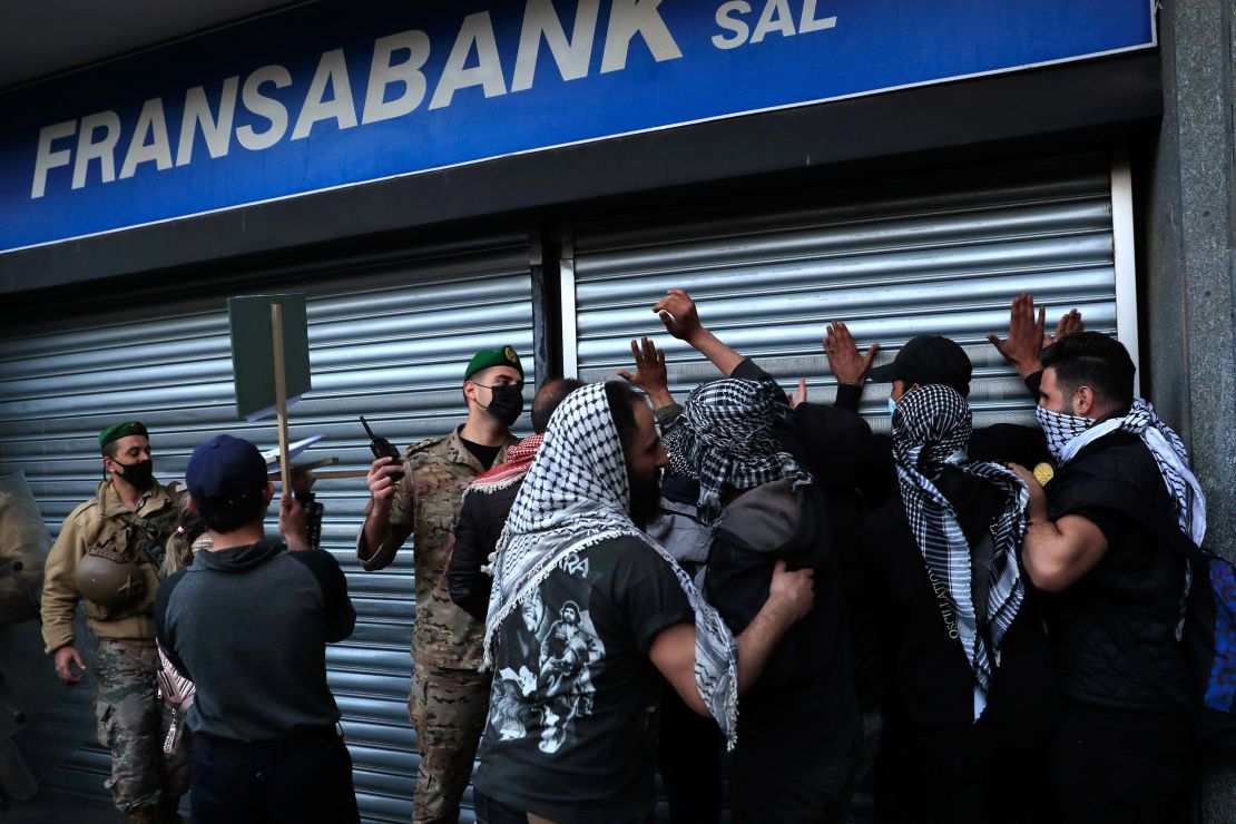 An army officer pushes back protesters who were trying to break down a bank door during a protest demanding that local banks allow people to withdraw their money on February 26. 