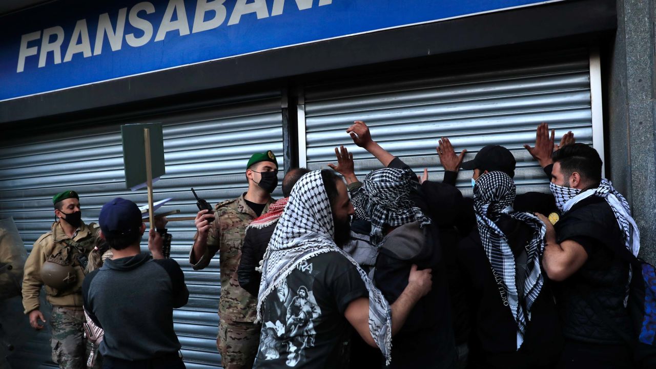 An army officer pushes back protesters who were trying to break down a bank door during a protest demanding that local banks allow people to withdraw their money on February 26.