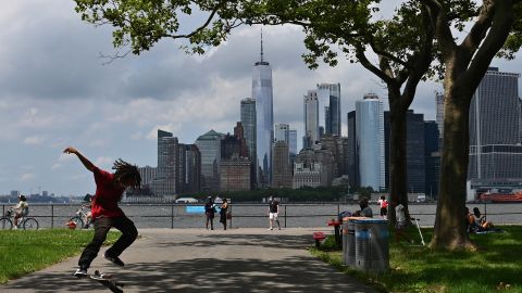 A man skateboards with the Manhattan skyline visible in the distance as people visit Governors Island on July 15, 2020 in New York City. 