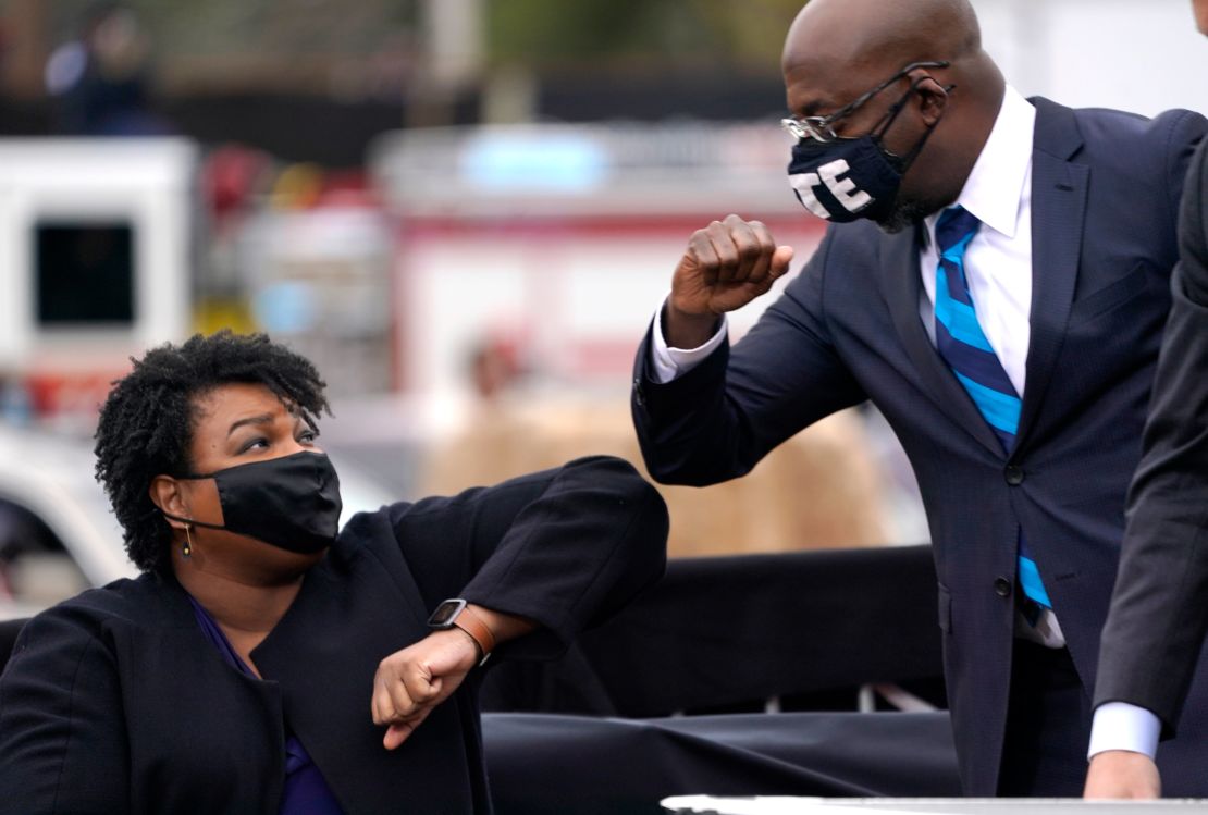 US Senate candidate Raphael Warnock bumps elbows with voting rights leader Stacey Abrams during a campaign rally for Joe Biden on December 15, 2020, in Atlanta.
