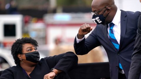 US Senate candidate Raphael Warnock bumps elbows with voting rights leader Stacey Abrams during a campaign rally for Joe Biden on December 15, 2020, in Atlanta.