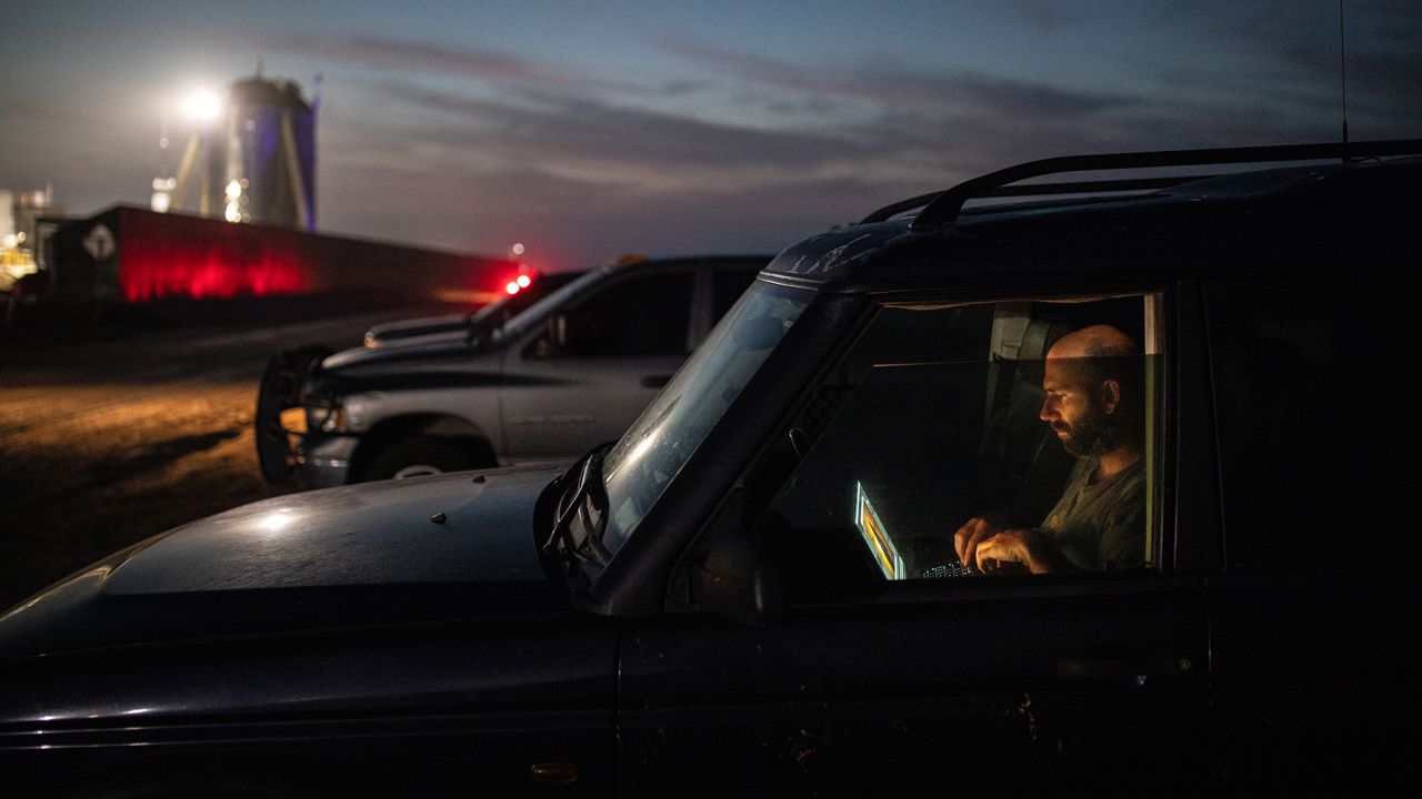 Jack Beyer edits photographs in his vehicle near the SpaceX launch site.
