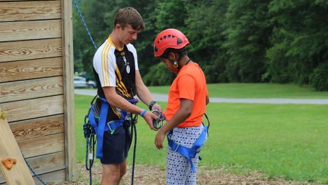 Summer camps have been planning with Covid-19 protocols in mind. In this August 2017 photo, staffer Joe Gilligan helps a camper with safety gear at Camp Sloane YMCA in Lakeville, Connecticut. The camp did not offer programs in 2020.