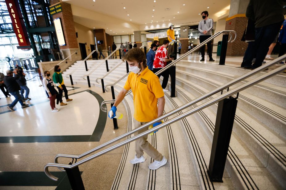 A staff member sprays disinfectant on a handrail at Bankers Life Fieldhouse in Indianapolis.