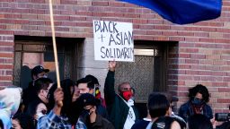A demonstrator wearing a face mask and holding a sign calling for "Black Asian Solidarity" takes part in a rally "Love Our Communities: Build Collective Power" to raise awareness of anti-Asian violence, at the Japanese American National Museum in Little Tokyo in Los Angeles, California, on March 13, 2021. - Reports of attacks, primarily against Asian-American elders, have spiked in recent months -- fuelled, activists believe, by talk of the "Chinese virus" by former president Donald Trump and others. 