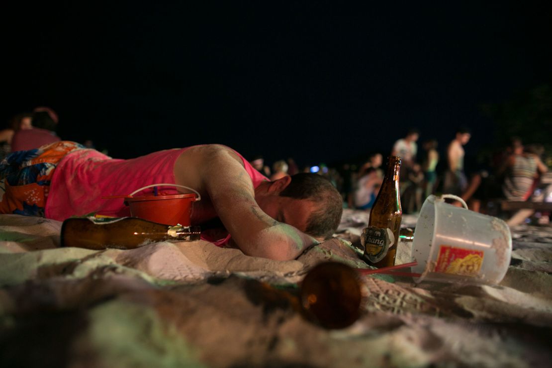 A man sleeps on the beach just before sunrise at the Full Moon Party on Haad Rin beach in 2013.