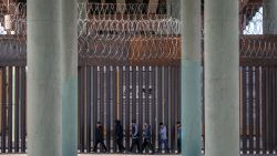 Undocumented immigrants walk along the U.S.-Mexico border wall after they ran across the shallow Rio Grande into El Paso on March 17, 2021 in Ciudad Juarez, Mexico.