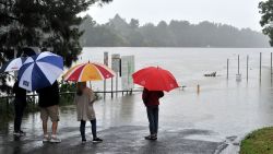 Residents look at the swollen Nepean river during heavy rain in western Sydney on March 20, 2021, amid mass evacuations being ordered in low-lying areas along Australia's east coast as torrential rains caused potentially "life-threatening" floods across a region already soaked by an unusually wet summer. (Photo by Farooq KHAN / AFP) (Photo by FAROOQ KHAN/AFP via Getty Images)