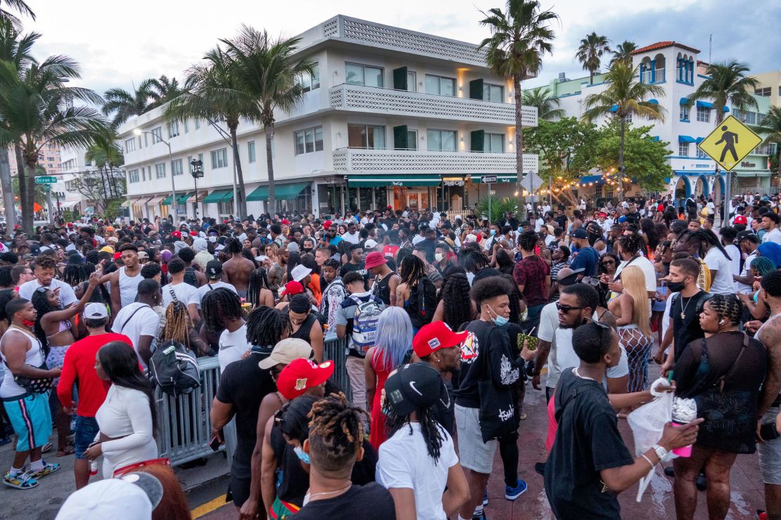 A large crowd of people gathers on a walkway near the beach in Miami Beach on Saturday.