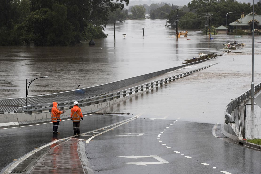 Traffic controllers stand at the Hawkesbury River Bridge submerged by floodwaters in Windsor, New South Wales, on March 22.