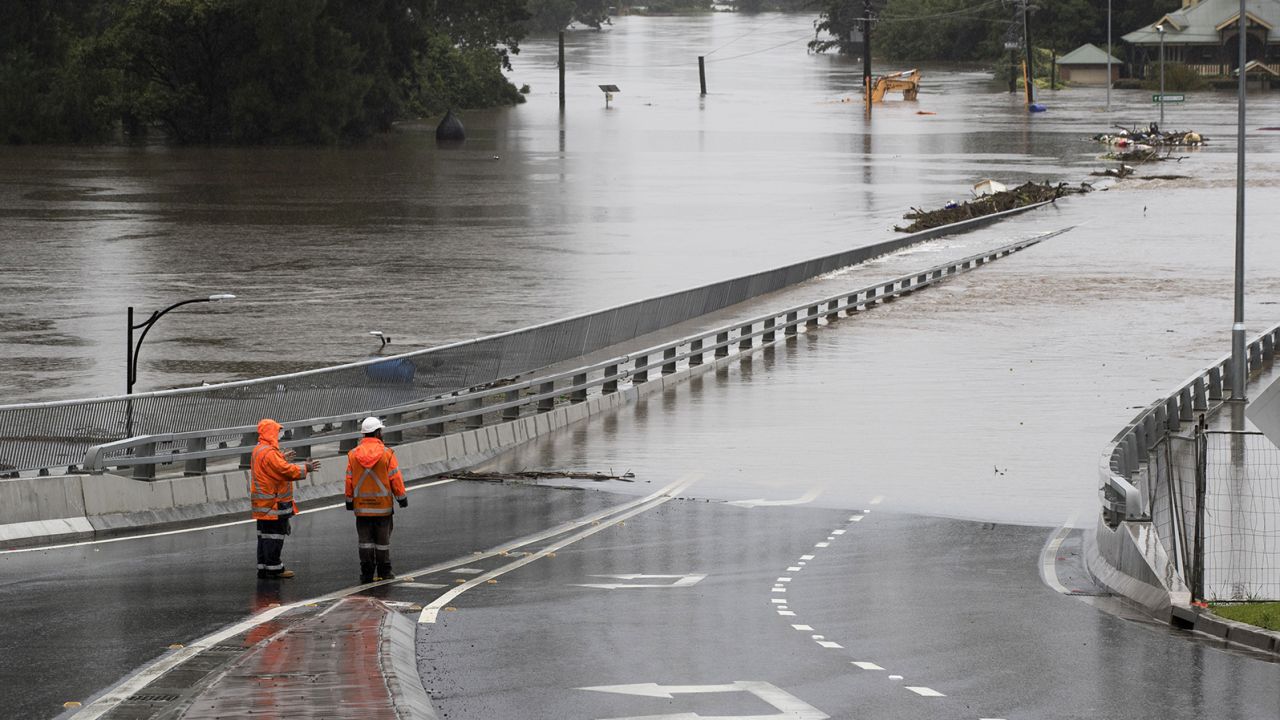 Traffic controllers stand at the Hawkesbury River Bridge submerged by floodwaters in Windsor, New South Wales, on March 22.