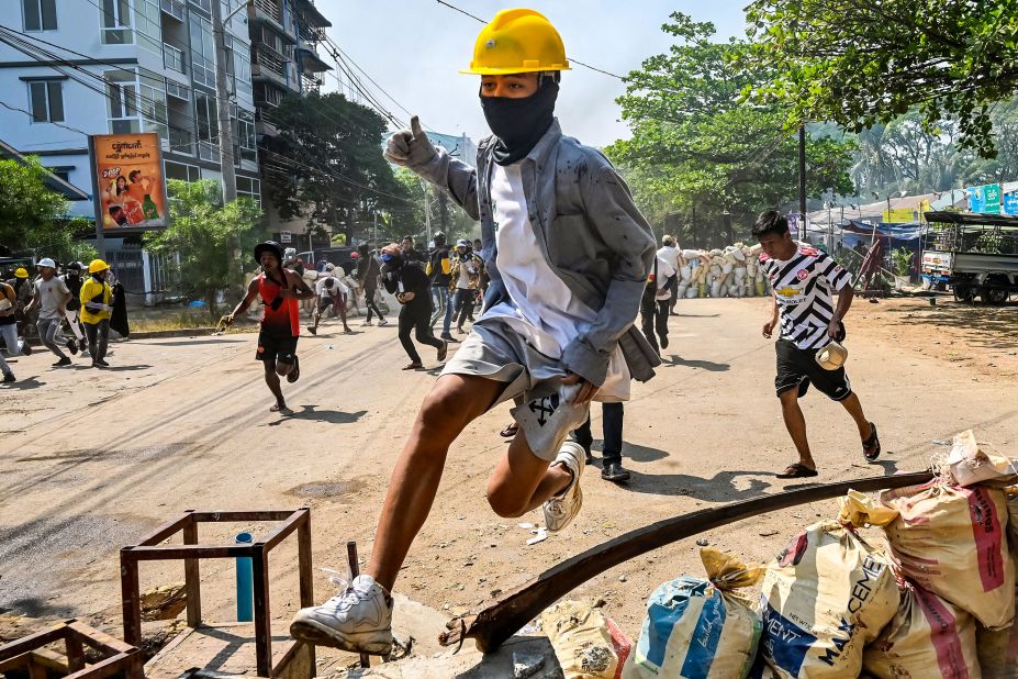 An anti-coup protester jumps over a makeshift barricade in Yangon on March 19.