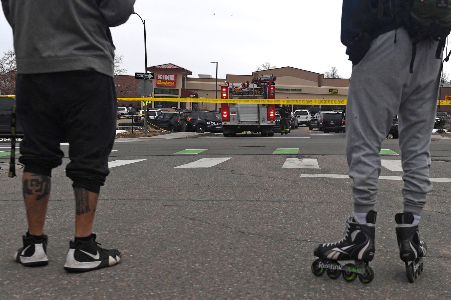 People observe the response behind police tape.