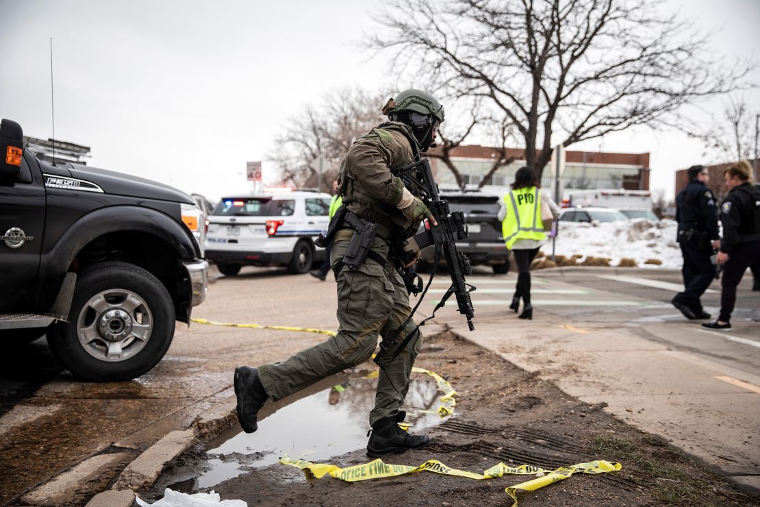 A SWAT team member runs toward the supermarket where a gunman opened fire.