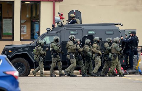 Police use an armored vehicle as a shield to move from one side of the building to the other.