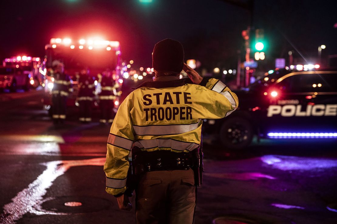 A Colorado State Police officer salutes as a procession carrying the body of a fellow officer leaves King Sooper's grocery store.