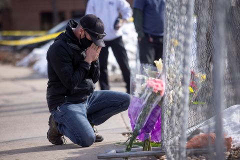 Conrad Wright leaves flowers at the scene on Tuesday, the day after the shooting.
