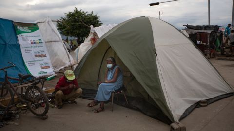 An elderly woman sits outside a tent in Lima, Honduras, where she lives after losing her home in last year's hurricanes Eta and Iota. Devastation from the storms and the economic damage of the Covid-19 pandemic have added to the forces that drive Hondurans to migrate.