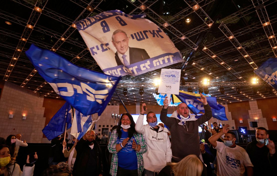 Likud party supporters wave flags bearing the party name and the face of Netanyahu on March 23. 