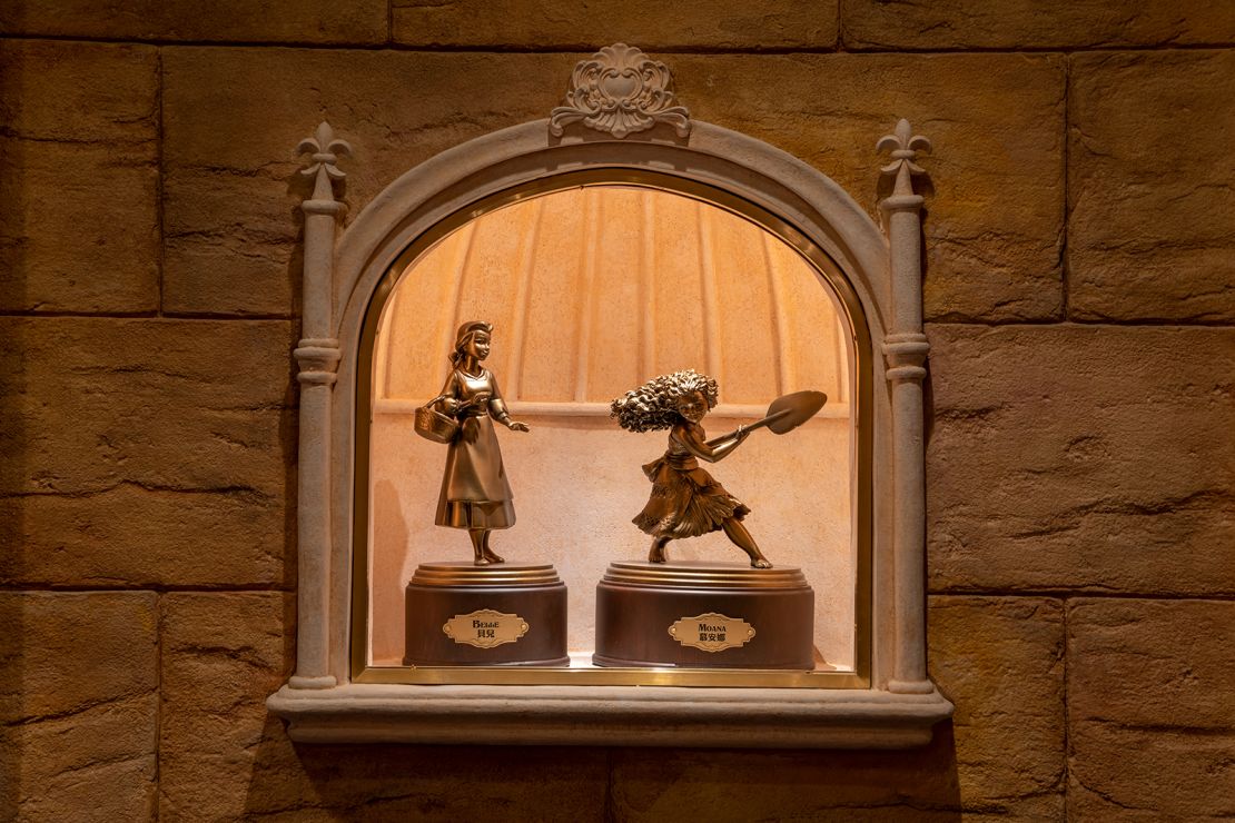 Bronze statues of princesses from "Beauty and the Beast" (1991) and "Moana" (2016) stand side by side in the new castle.