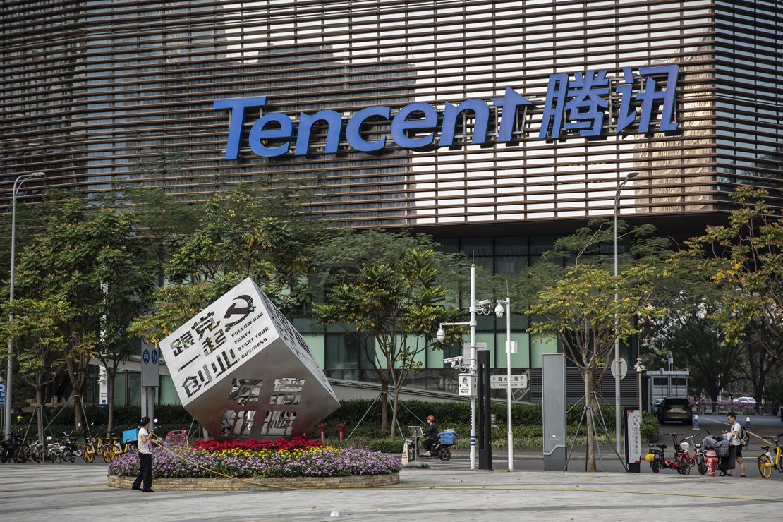 A worker watering flowers around an installation reading "Follow Our Party Start Your Business," in front of Tencent's headquarters in Shenzhen, China in March.