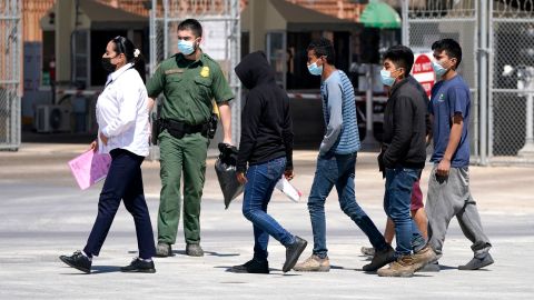 Migrants, who were caught trying to come into the United States, are led by a US Customs and Border Protection agent, second from left, at the McAllen-Hidalgo International Bridge while being deported to Reynosa, Mexico, on Thursday, March 18, 2021, in Hidalgo, Texas. 