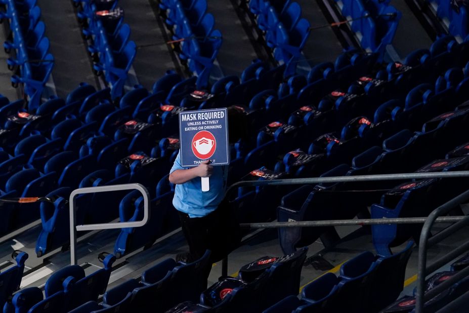 An usher holds a sign reminding fans to wear a mask.