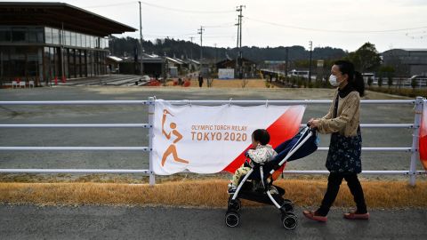 A woman pushes a child in a stroller outside a torch relay venue in Naraha town, March 25.