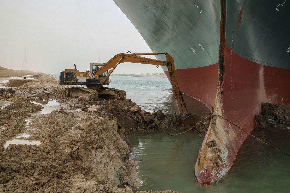 An excavator attempts to free the front end of the Ever Given.