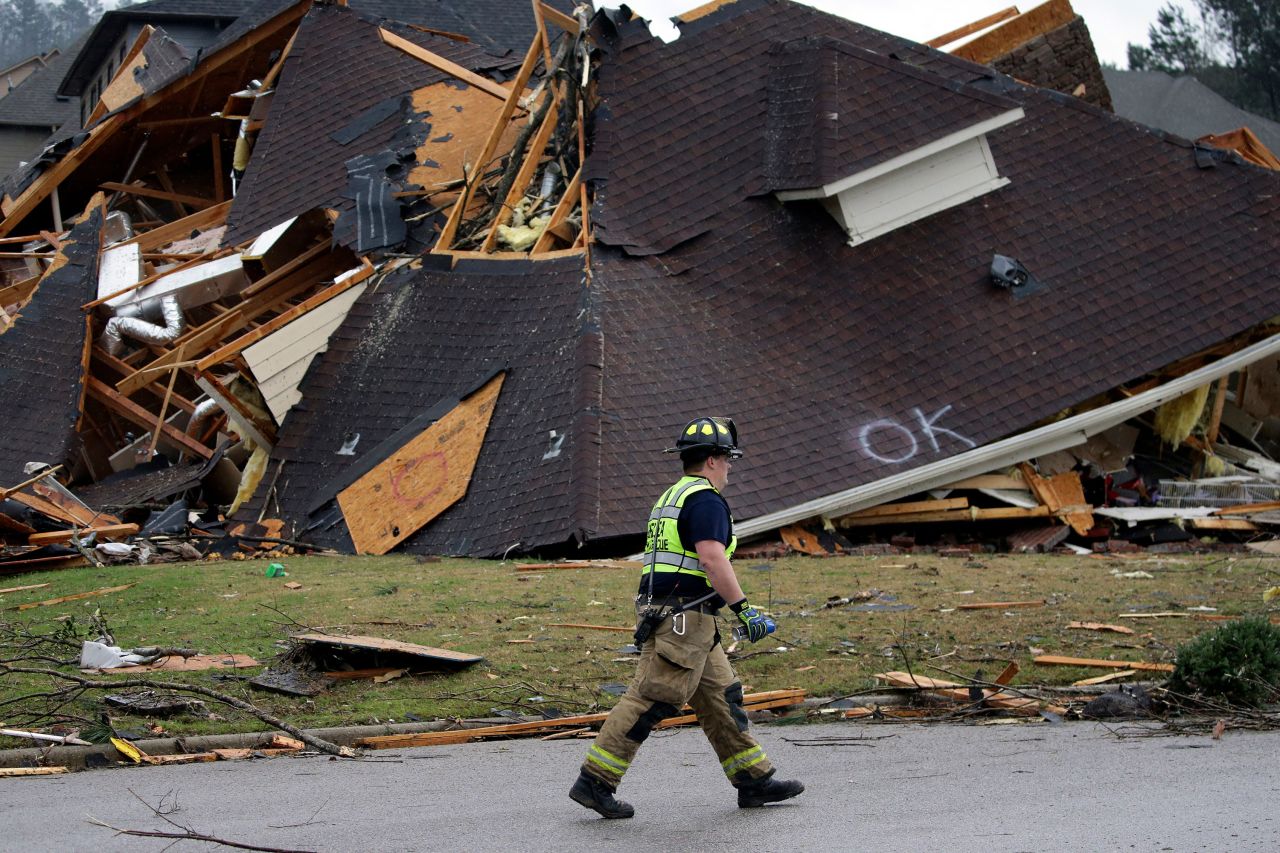 A firefighter walks past a damaged house in the Eagle Point neighborhood.