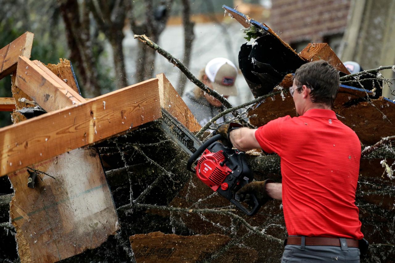 Eagle Point residents cut away debris after a tornado touched down Thursday.
